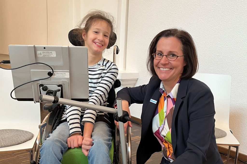 Mehrere Frauen und ein Mädchen sitzen an einem langen Tisch mit vielen Mikrofonen