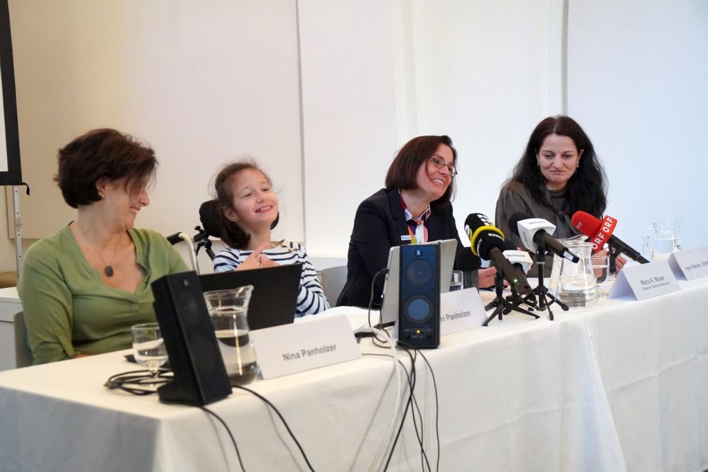 Eine Jugendliche mit Sprachcomputer mit einer Frau auf einer Pressekonferenz